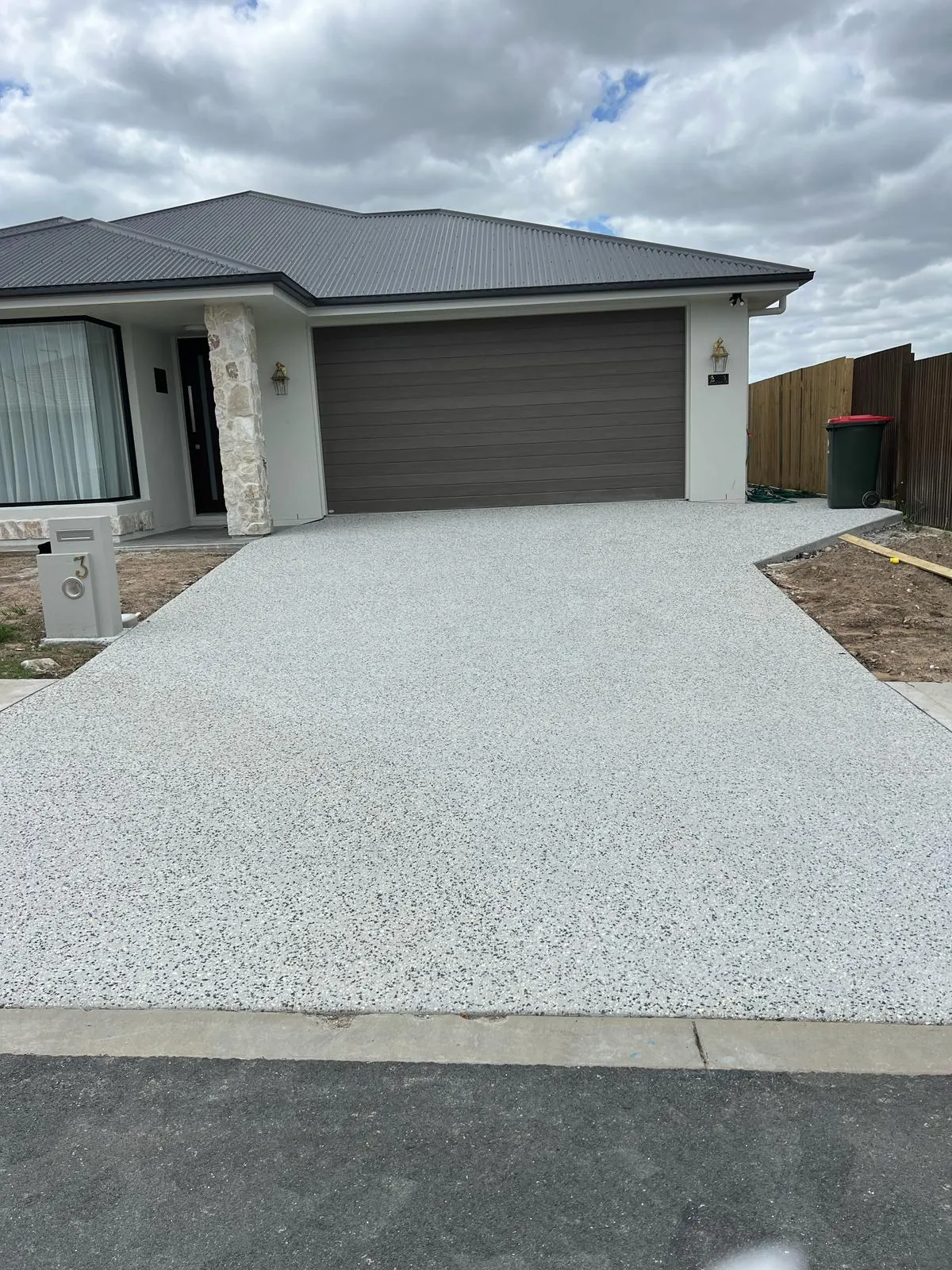 Exposed aggregate concrete driveway leading to double garage of a Brisbane home